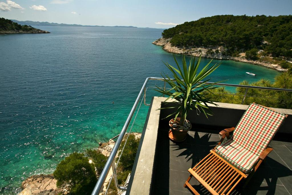 una silla y una planta en un balcón con vistas al agua en Vila Filipovic, en Milna