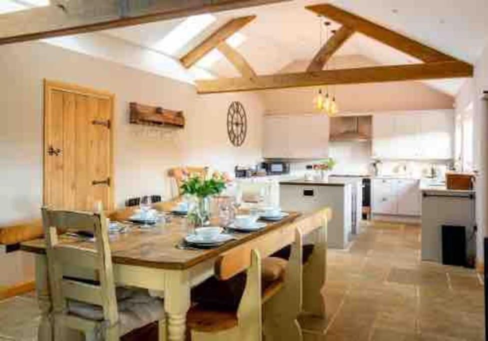 a large kitchen with a wooden table and chairs at Dovecote in Chipping Campden