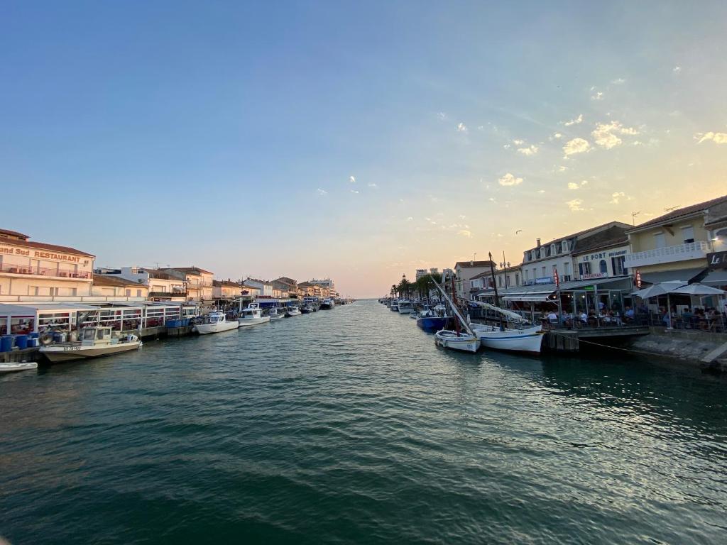 un groupe de bateaux amarrés dans une rivière avec des bâtiments dans l'établissement charmant studio dans résidence en bord de mer, au Grau-du-Roi