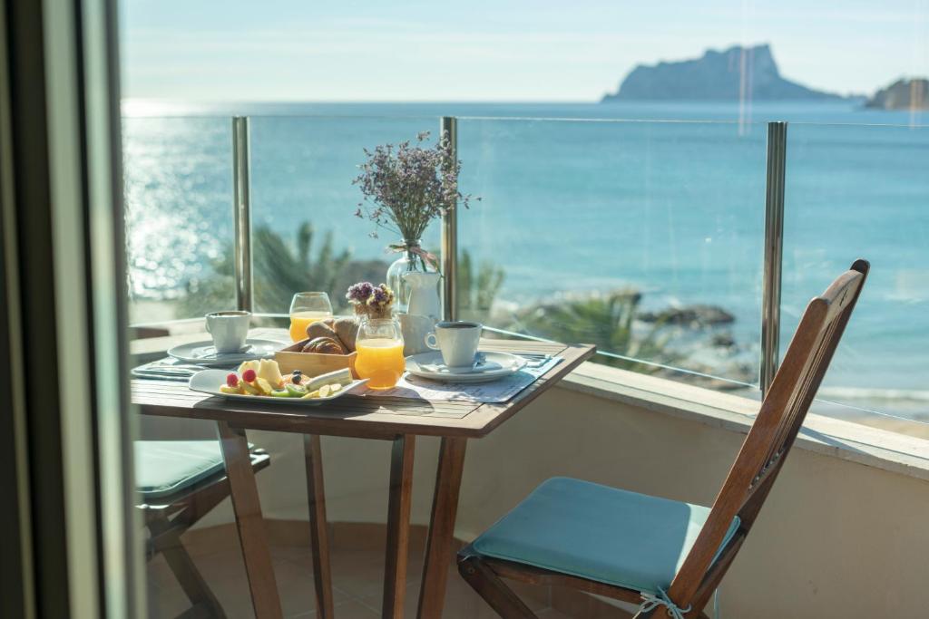 uma mesa com um prato de comida numa varanda com o oceano em La Sort Boutique Hotel em Moraira