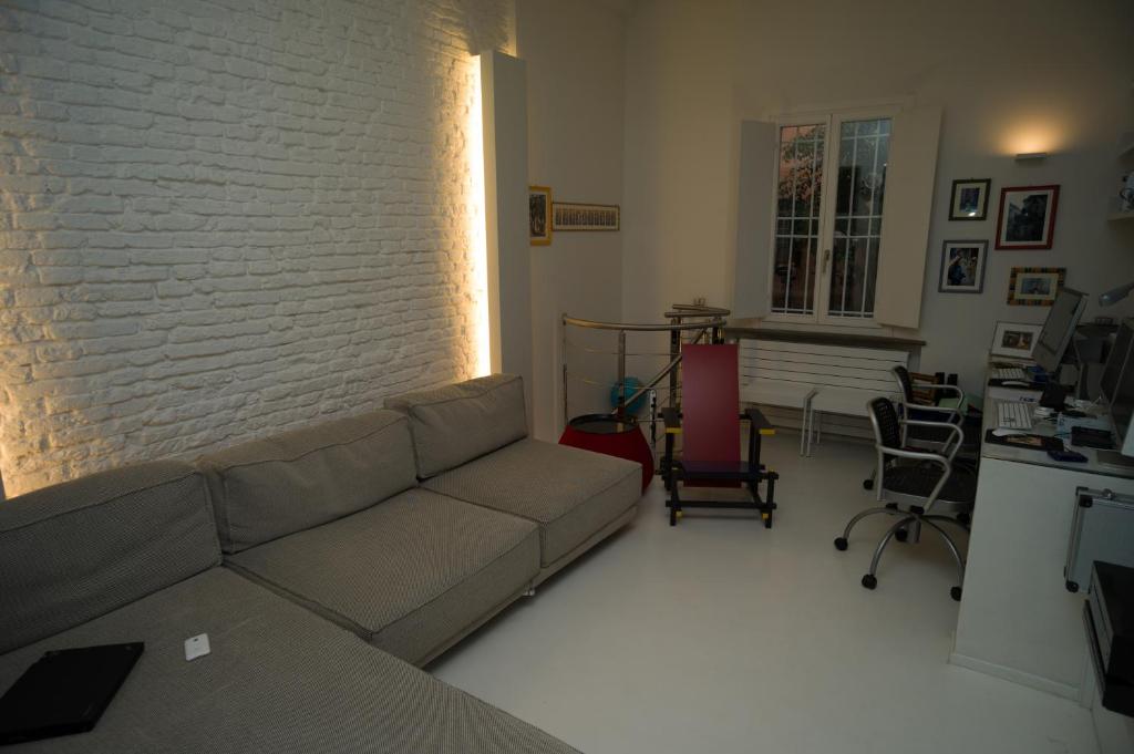 a living room with a couch and a brick wall at Elegant And Modern Loft In Medieval Bologna in Bologna