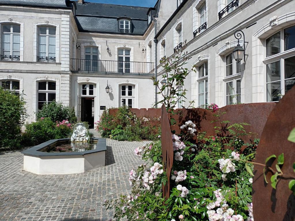 um pátio com uma fonte em frente a um edifício em Hôtel Loysel le Gaucher em Montreuil-sur-Mer