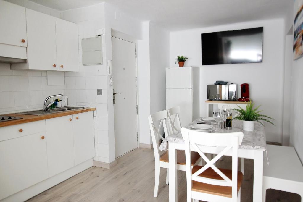 una cocina blanca con mesa y sillas. en Apartamento los Pirineos Sabi, en Sabiñánigo