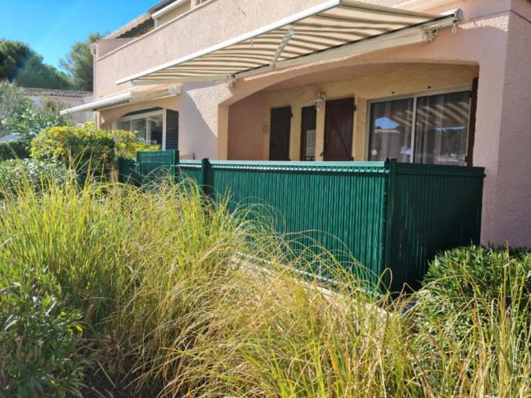 une clôture verte devant une maison dans l'établissement CIGALINES Très beau T2 piscine Pinède Cap d'Agde, au Cap d'Agde