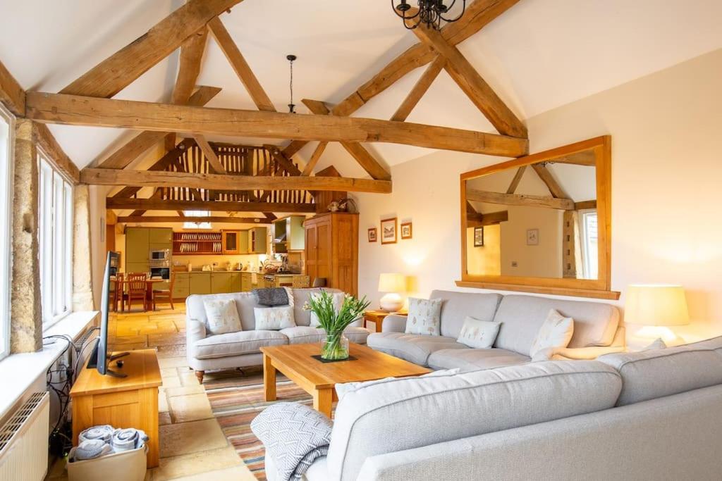 a living room with couches and a table at Groves Barn at Norton Grounds in Chipping Campden