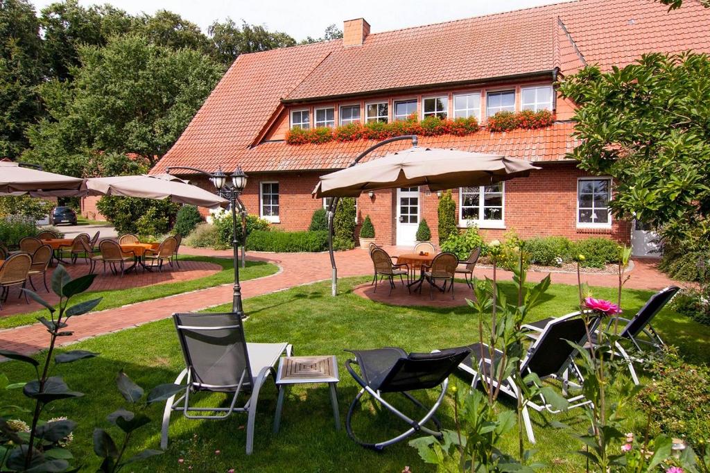 um jardim com cadeiras, mesas e guarda-sóis em frente a uma casa em Ferienhof Große Drieling em Greven