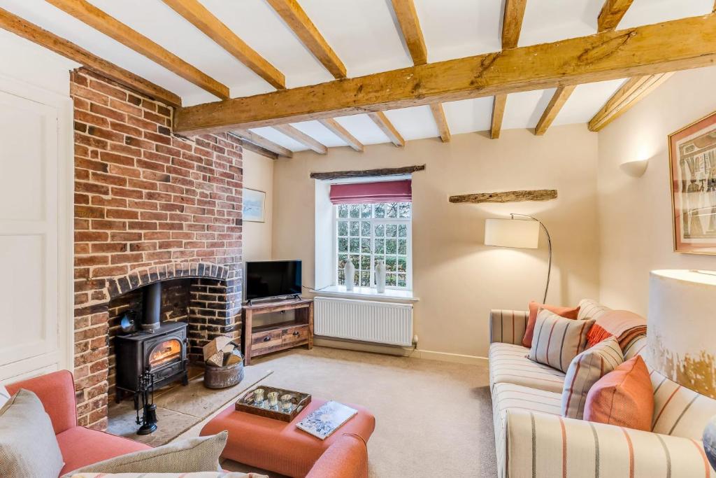 a living room with a fireplace and a brick wall at Brand Hill Cottage with Hot Tub in Loughborough