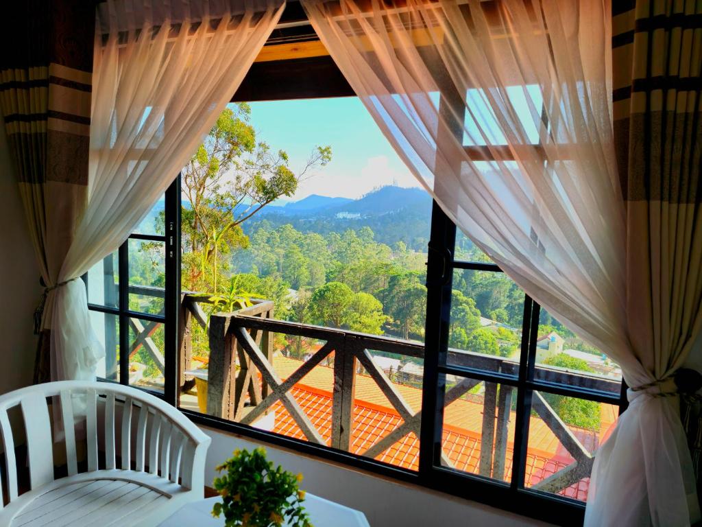 una camera da letto con una grande finestra con vista sulle montagne di Chez Allen a Nuwara Eliya