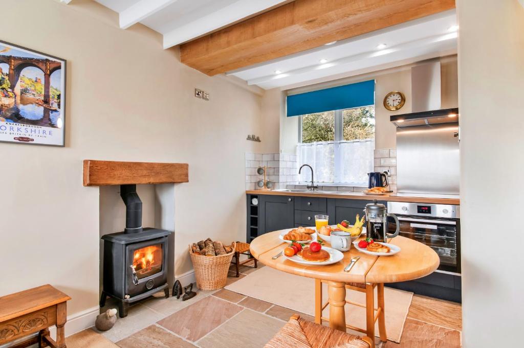 a kitchen with a table and a wood stove at Finest Retreats - Tyg Cottage near Masham, Fountains Abbey & Brimham Rocks in Ripon