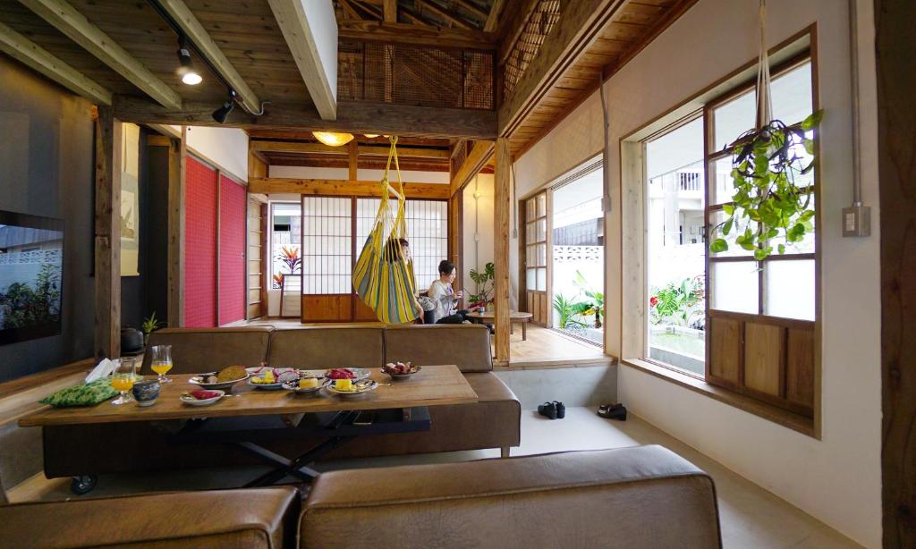 ロフトが付いた沖縄古民家で寛ぎの時間を 懐かしくて新しい 海野24 في نانجو: غرفة معيشة مع طاولة وكراسي وشخص