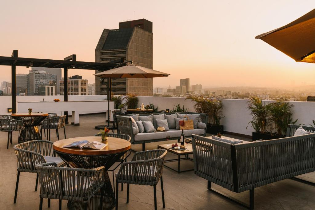 a rooftop patio with tables and chairs on a building at Sonder Aria in Mexico City