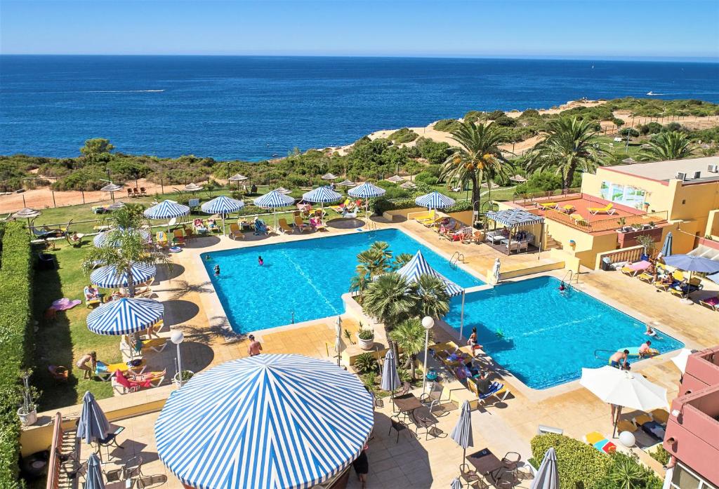 widok na basen z parasolami i ocean w obiekcie Hotel Baia Cristal Beach & Spa Resort w mieście Carvoeiro