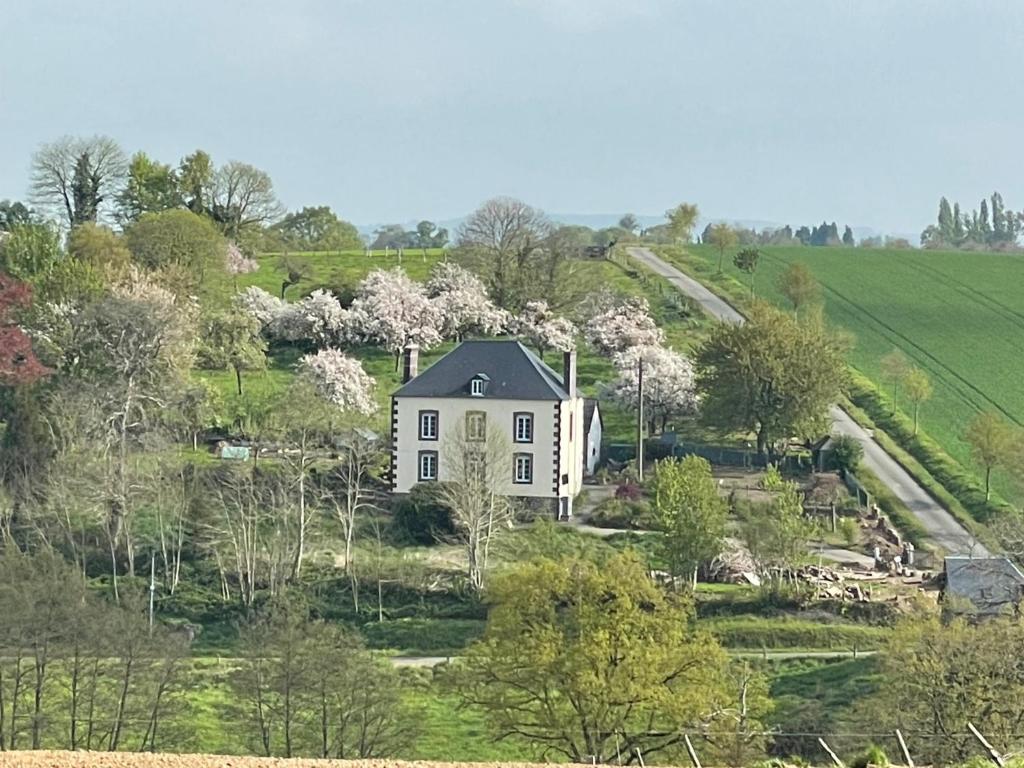 ein weißes Haus auf einem Hügel mit Bäumen in der Unterkunft La Houlardais in Soucé