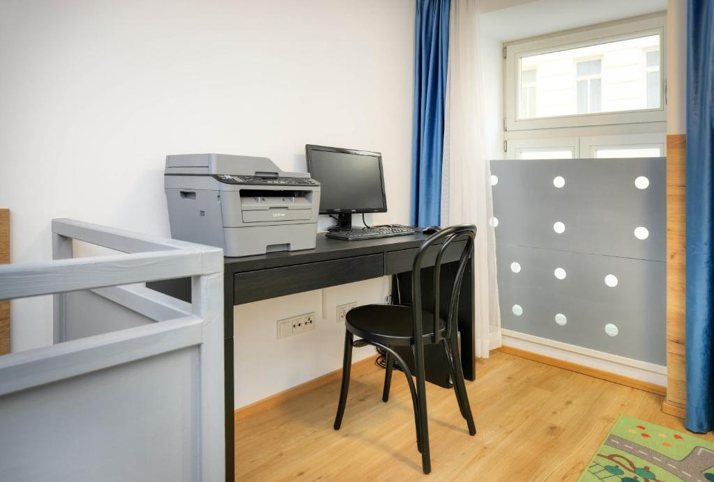 a room with a desk with a computer and a printer at Jimmy's Apartments Emerald in Vienna