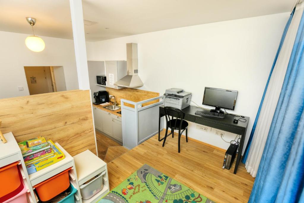 a room with a kitchen and a desk with a computer at Jimmy's Apartments Emerald in Vienna