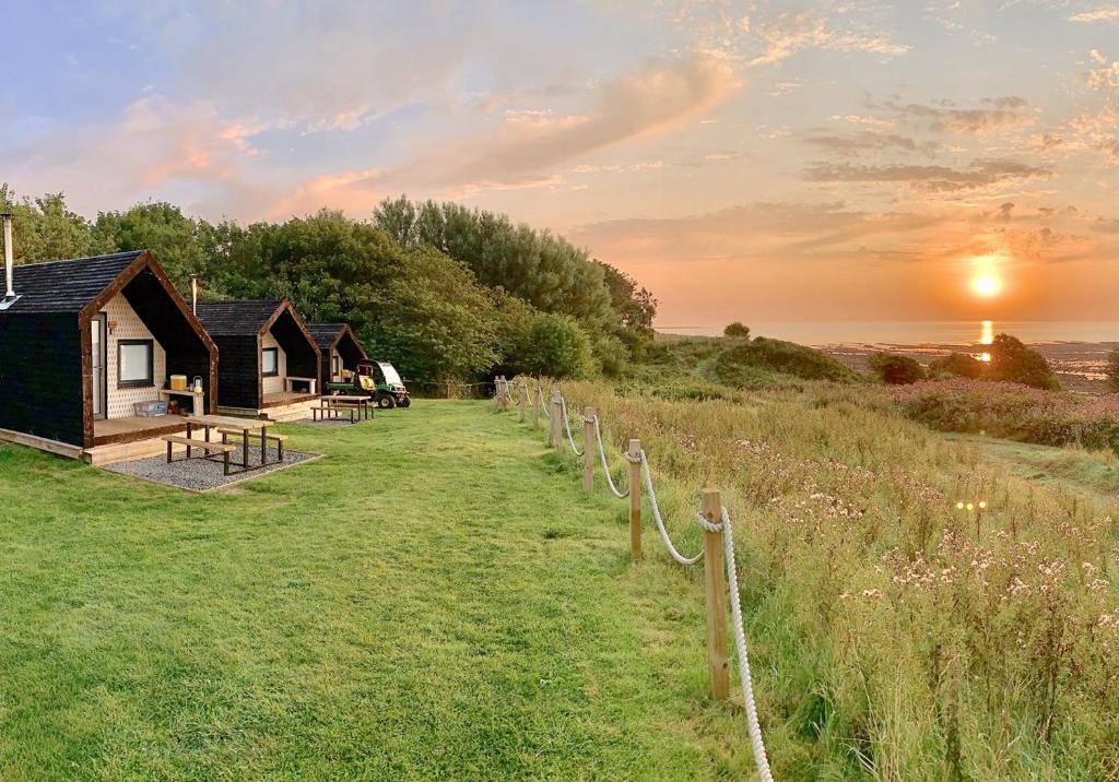 a row of cottages on the beach at sunset at St Aidan Beach Hut Alnmouth in Alnmouth