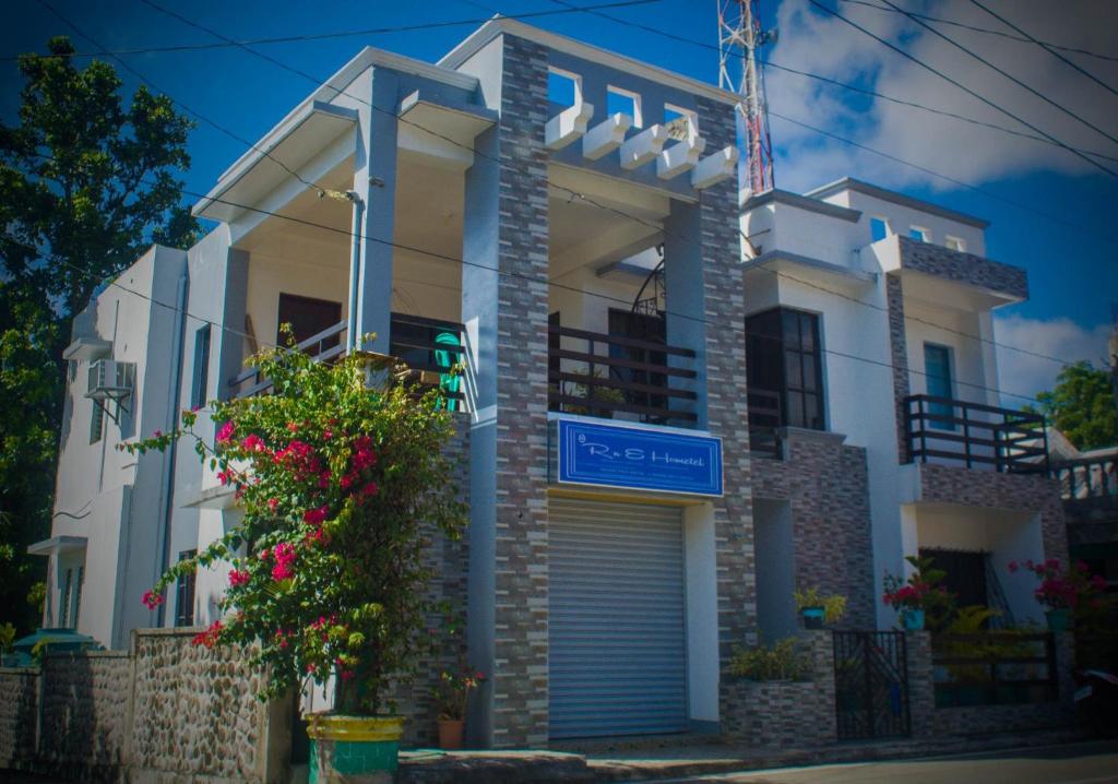 a white house with a blue sign in front of it at RnE Hometel Batanes in Ivana