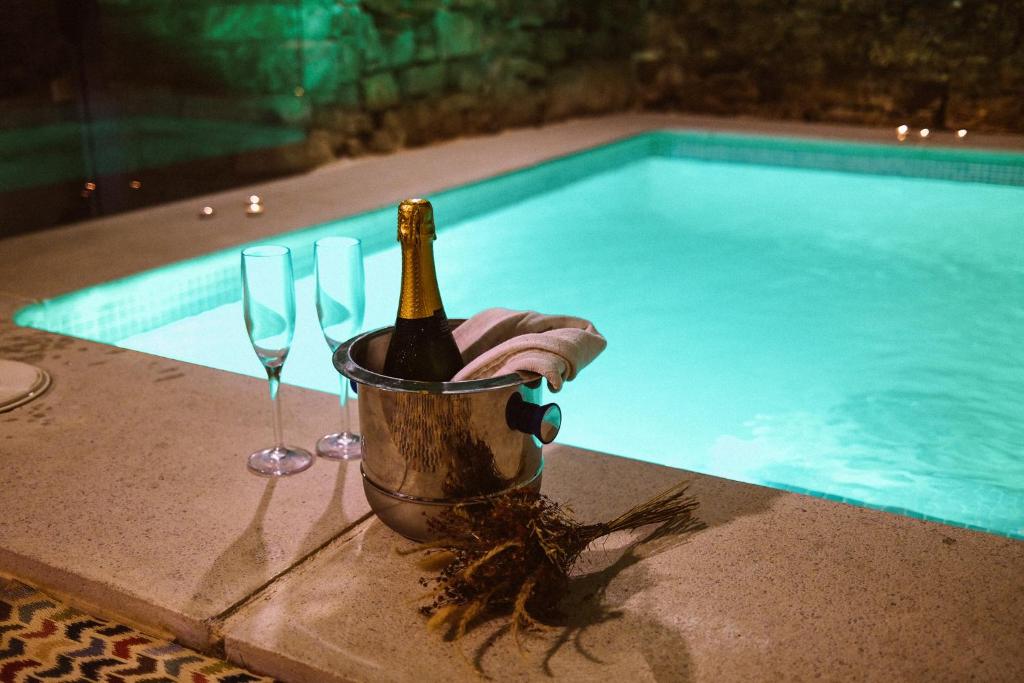 a bottle of champagne in a bucket next to a swimming pool at El Forn de Freixenet con servicios de un hotel in Lleida