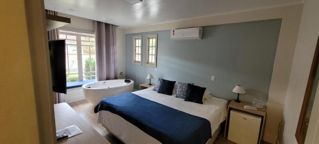 ein Schlafzimmer mit einem Bett, einer Badewanne und einem TV in der Unterkunft Pousada Do Conde in Campos do Jordão