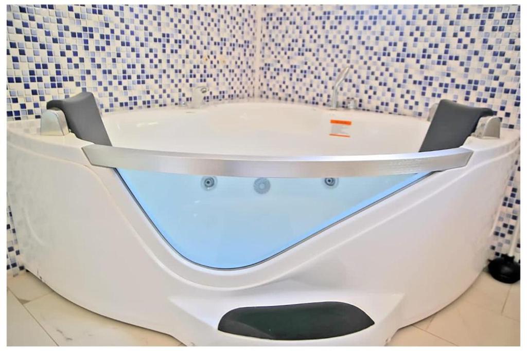 a white bath tub in a bathroom with a tile wall at Oasis Lawafossi in Bobo-Dioulasso