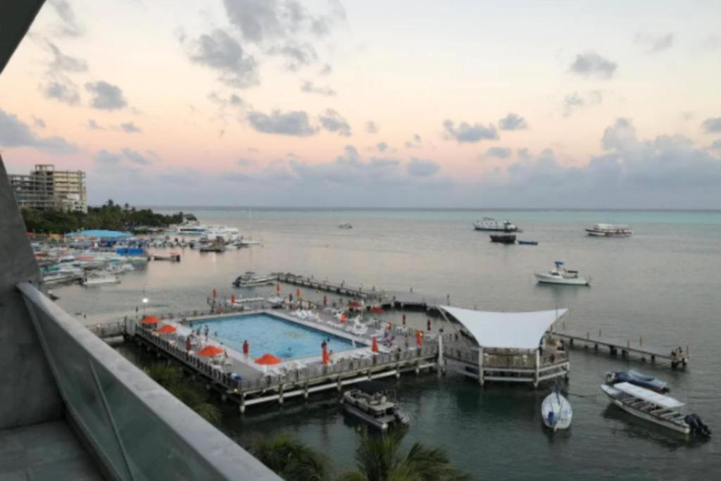 圣安德烈斯Apartamento con Vista al Mar en Sun Rise San Andrés的享有带水中船只的游泳池的景色