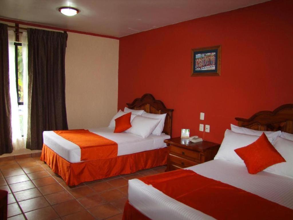 a hotel room with two beds with red walls at Hotel Oaxaca Dorado in Oaxaca City