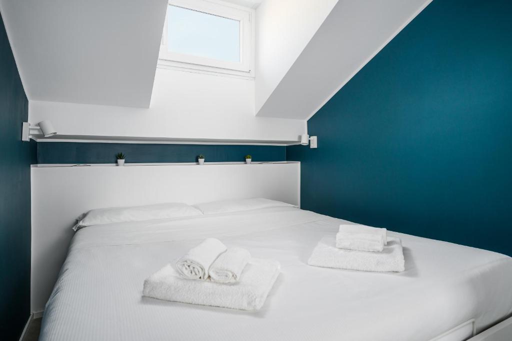 un letto bianco con due asciugamani e una finestra di Design Attic porta venezia centrale 65m2 - self check-in a Milano
