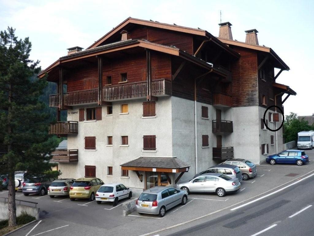 a large building with cars parked in a parking lot at Studio cabine Le Charvet in Le Grand-Bornand