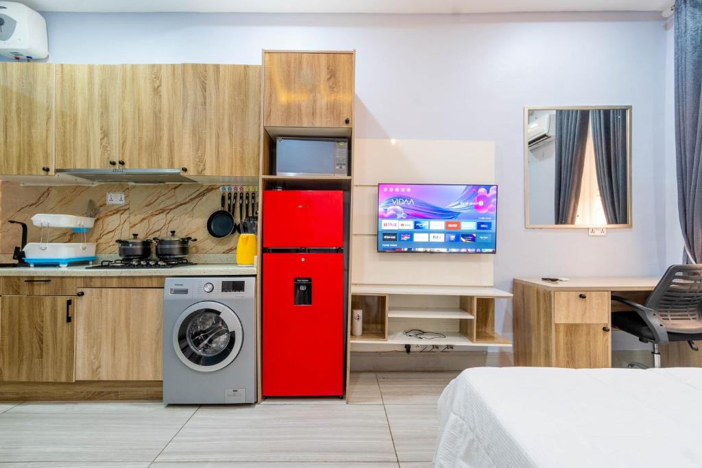 Il comprend une cuisine équipée d'un réfrigérateur rouge et d'un lave-linge. dans l'établissement Cecilia Homes, à Lekki