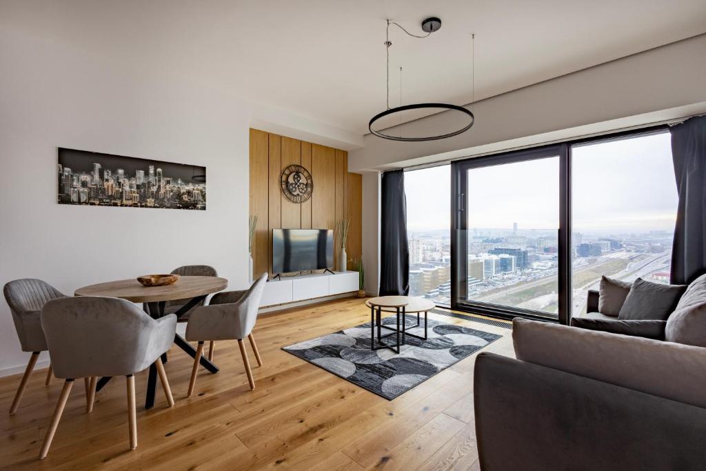 - un salon avec un canapé et une table avec des chaises dans l'établissement In The Sky - Apartment West 65 Tower, à Belgrade