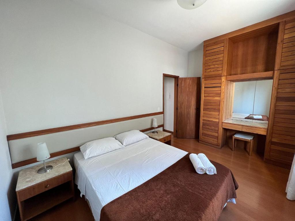 a bedroom with a white bed and wooden cabinets at Locking's Funcionários 6 in Belo Horizonte