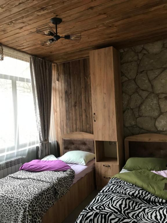 two beds in a room with wooden ceilings at David guest house LOFT Коттеджи на берегу реки in Dilijan
