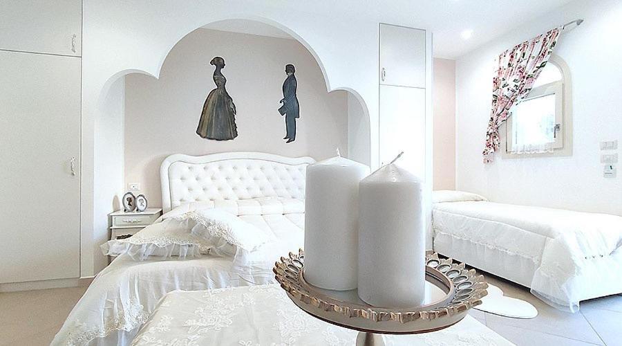 una camera bianca con un letto e un tavolo con candele di Casa il piccolo principe a Carovigno