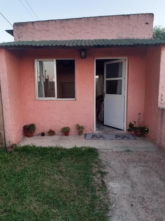 una casa rosa con una puerta blanca en Alojamiento en Tacuarembó, en Tacuarembó