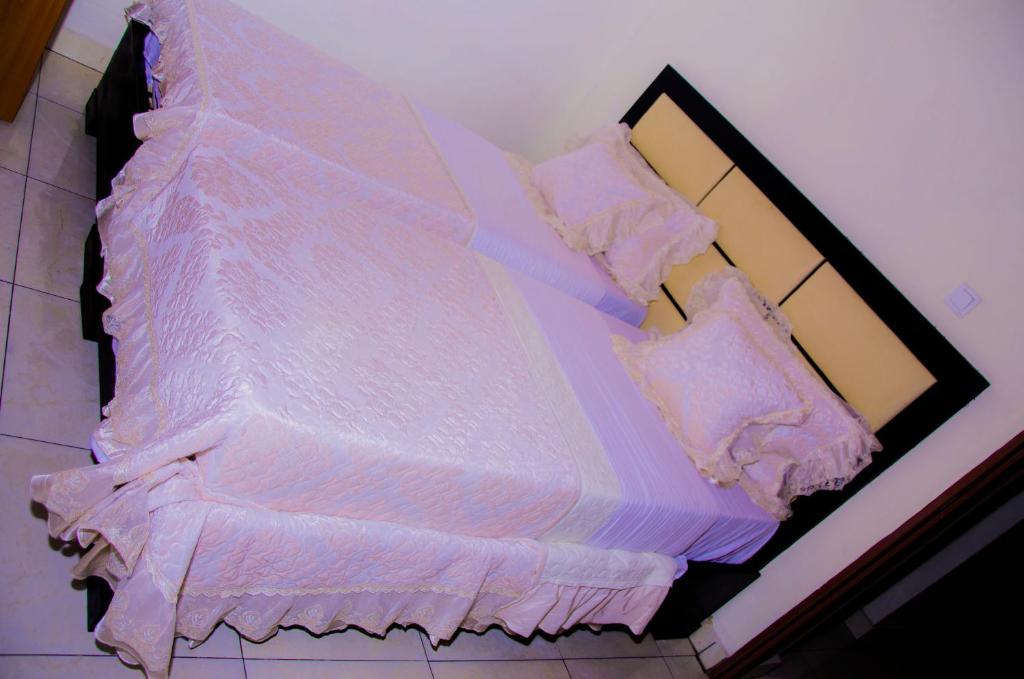 - un lit avec des draps et des oreillers blancs dans l'établissement PARADOR MOTEL KIGALI, à Kigali