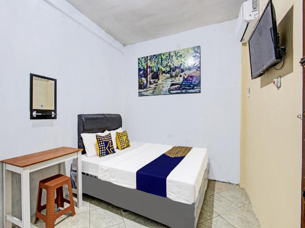 a bedroom with a bed and a desk and a tv at SPOT ON 92319 White House Syariah in Yogyakarta