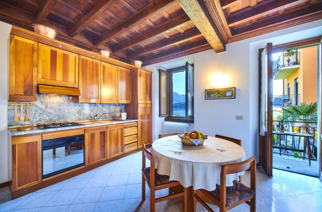 une cuisine avec des placards en bois et une table avec des chaises dans l'établissement Casa Mocchetti, à Lezzeno