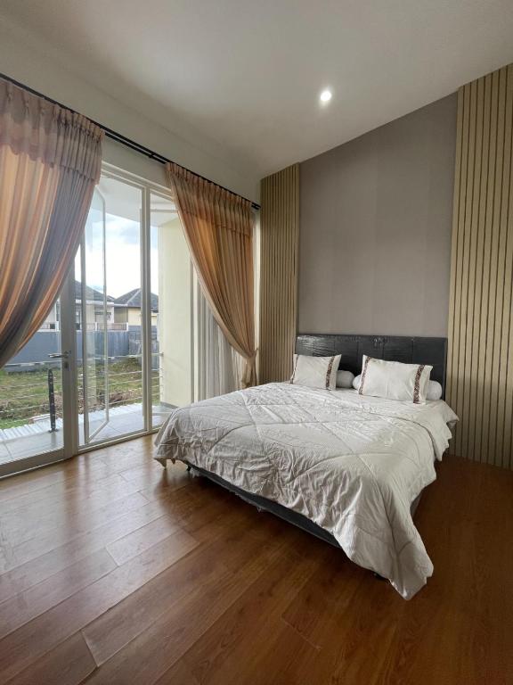 ein Schlafzimmer mit einem Bett und einem großen Fenster in der Unterkunft Apple eight 2BR Villa in Batu