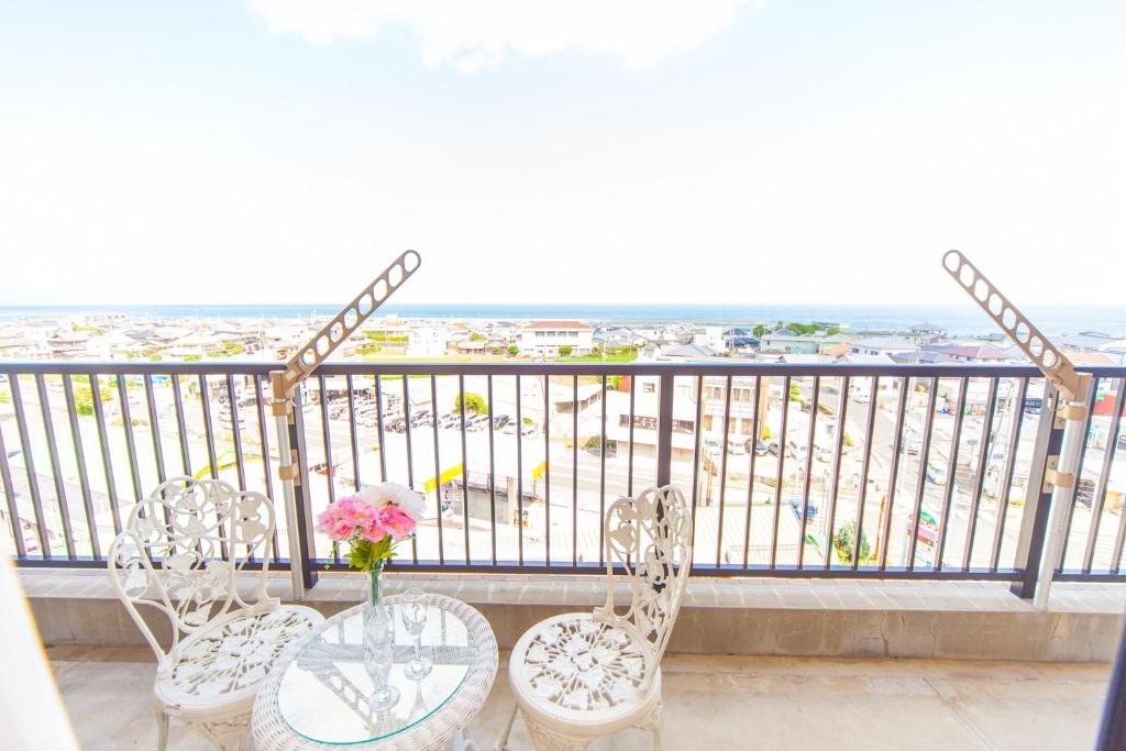 a balcony with two chairs and a table with a vase of flowers at Mansion Kitanomachi Room 408 - Vacation STAY 64438v in Awaji