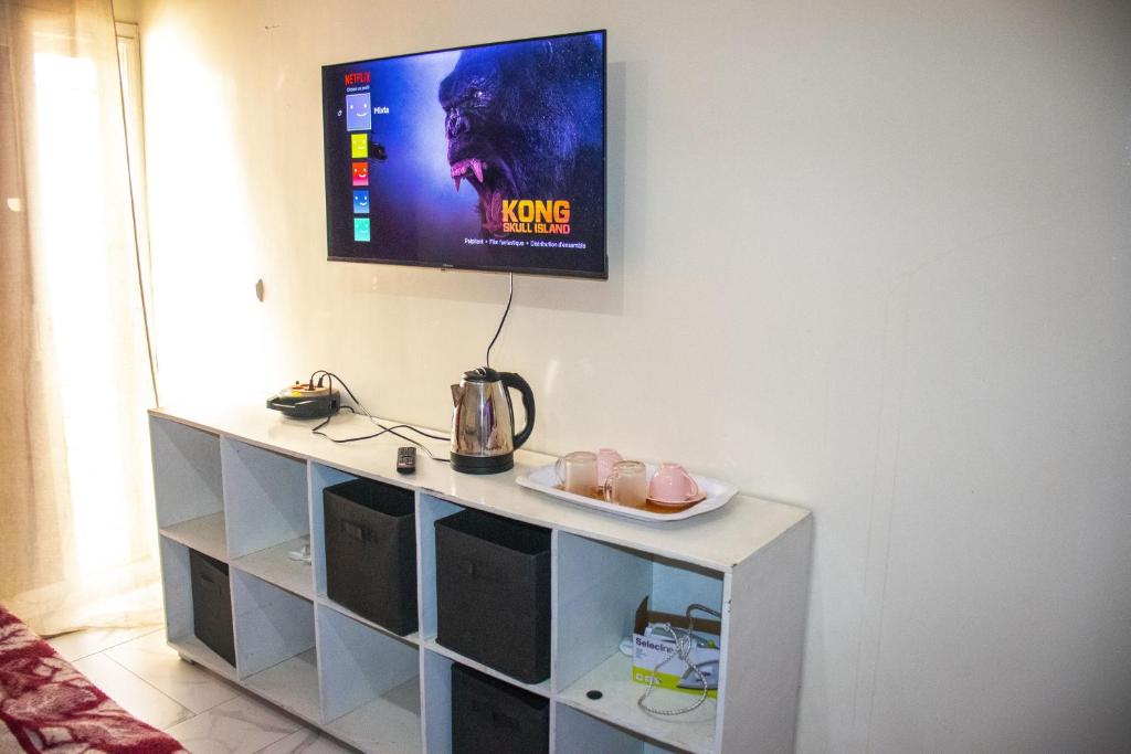 a tv hanging on a wall above a white cabinet at DALOU Chambre hôte, Cité mixta in Dakar