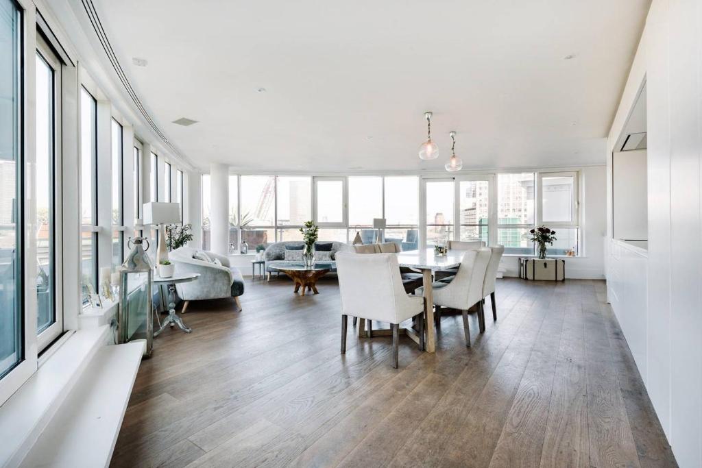 a dining room and living room with a table and chairs at Luxury Panoramic 3 bed with private terrace in London