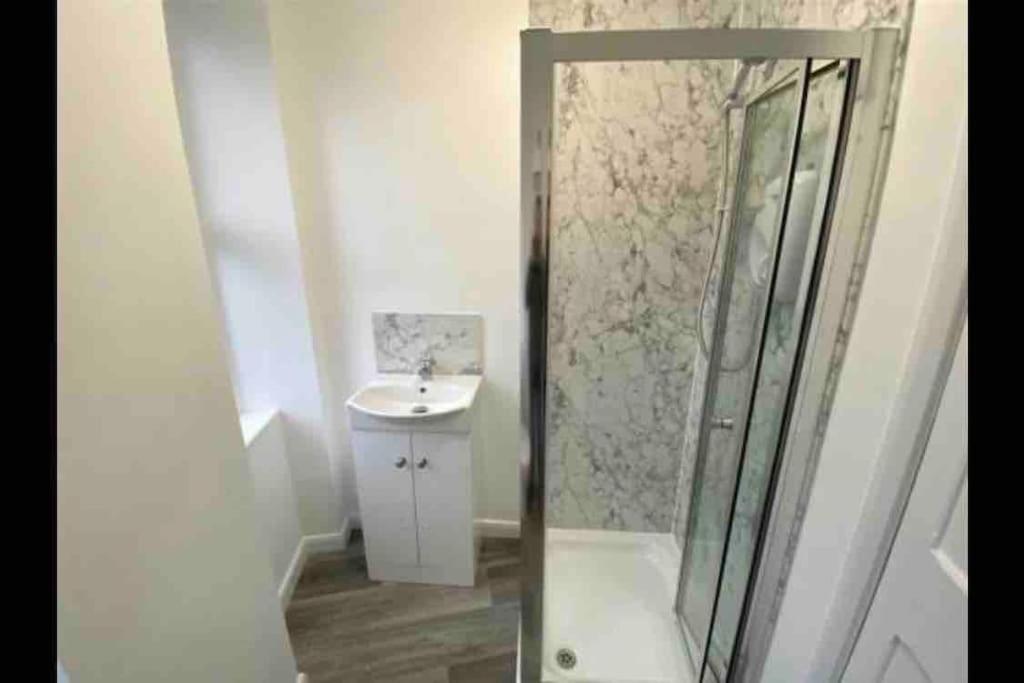 ein Bad mit einer Dusche und einem Waschbecken in der Unterkunft First floor apartment in Stratton, Bude in Stratton