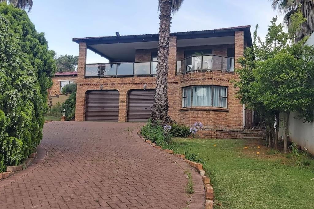 a brick house with a palm tree and a driveway at Phoenix, Langenhovenpark, Bfn near Inibos parkrun. in Bloemfontein