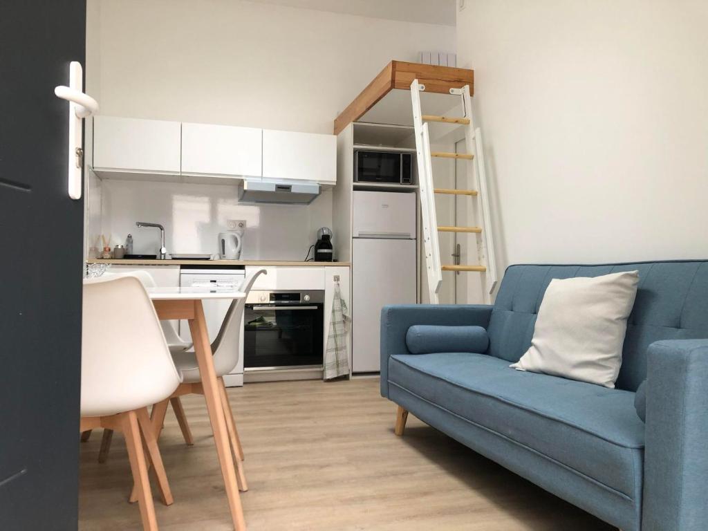 sala de estar con sofá azul y cocina en F2 équipé, 15mn de Paris, parking, climatisation, en Bourg-la-Reine