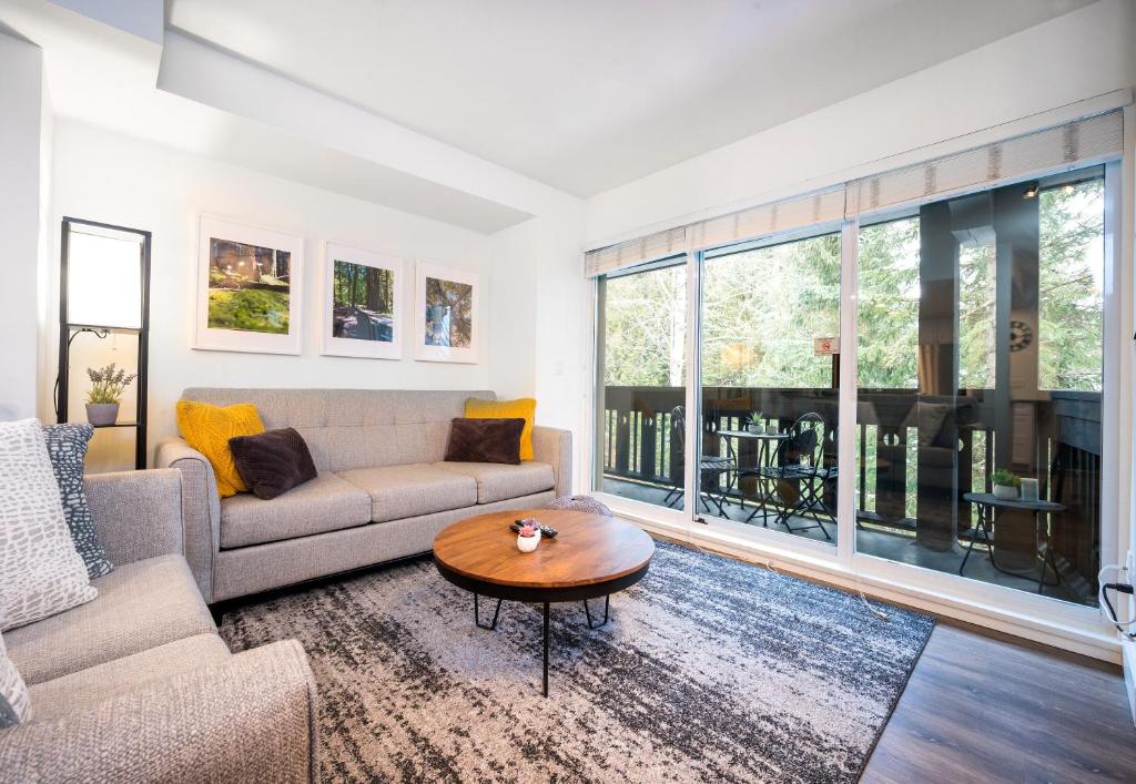 a living room with a couch and a table at Amazing Village Location with PRIVATE Hot Tub in Whistler