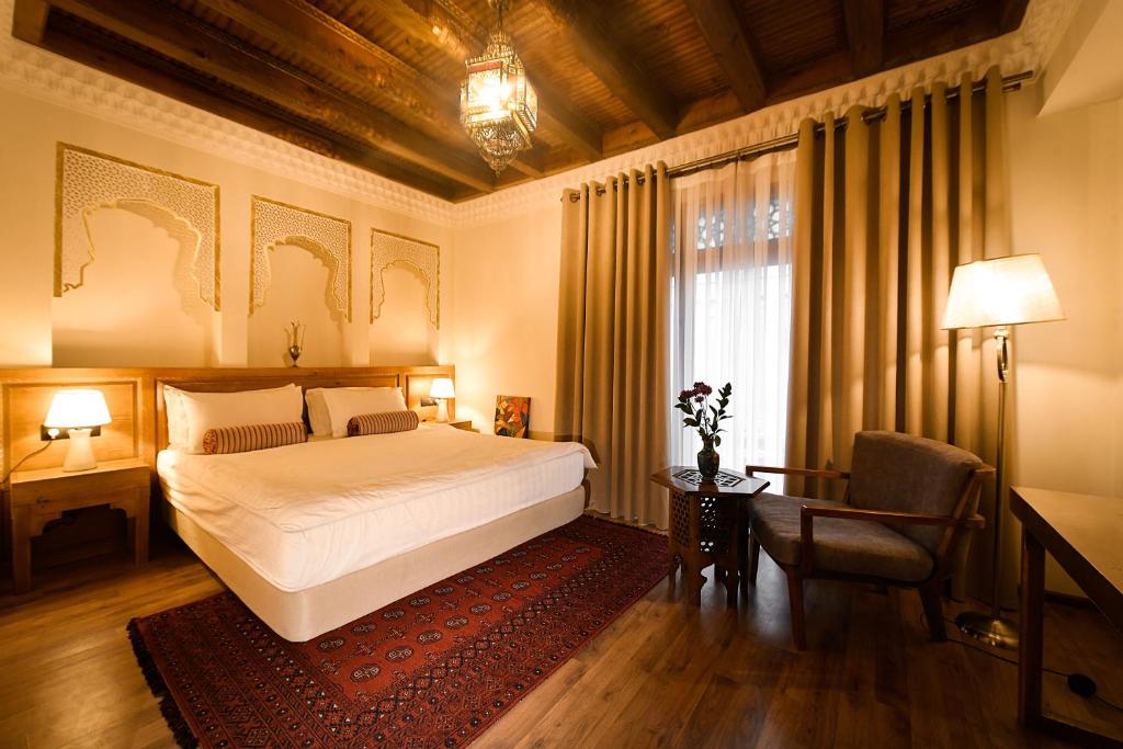 a bedroom with a bed and a desk and a window at Kukaldosh Boutique Hotel in Bukhara