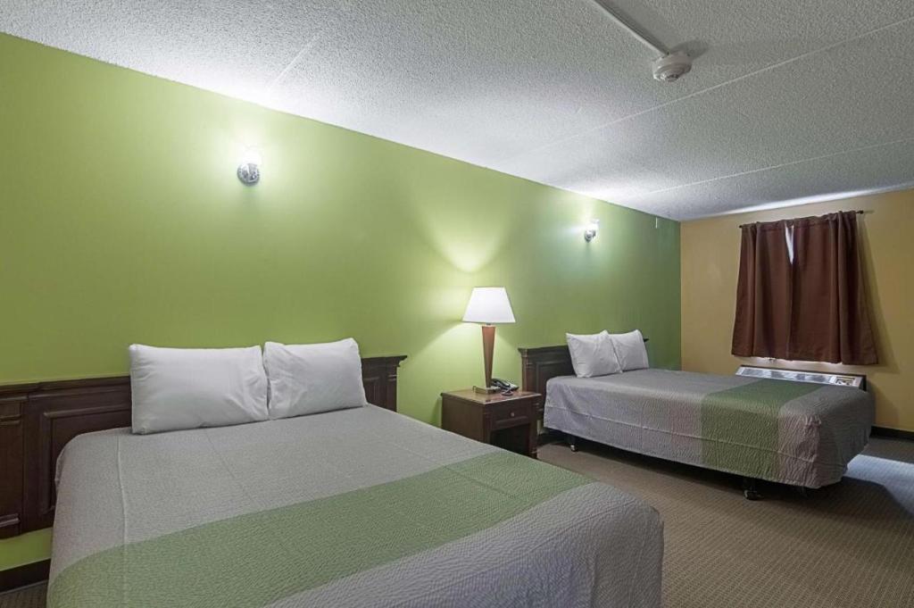 een hotelkamer met 2 bedden en groene muren bij LoneStar Inn and Suites in Sherman