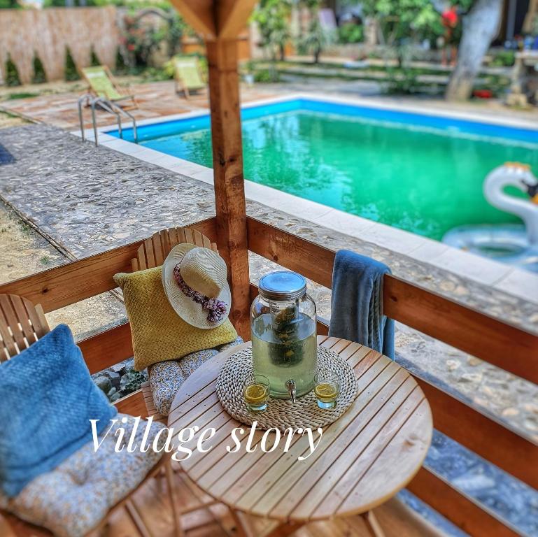 a table with a glass jar on it next to a swimming pool at Village Story kuća za odmor Plavna 