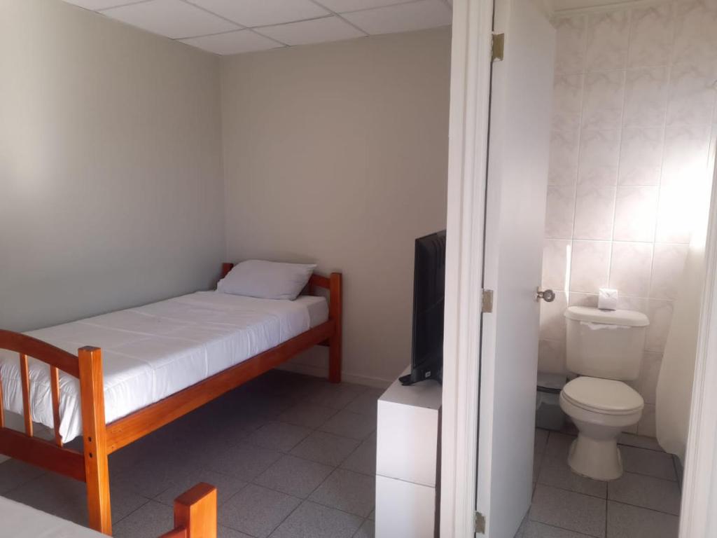 um quarto com uma cama, um WC e uma televisão em CasaLeon em Mejillones