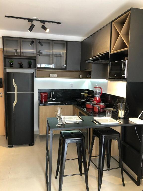 a kitchen with a black refrigerator and a table with stools at Studio Luxo Completo Independência 915- São Mateus in Juiz de Fora